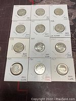 Image showing all 12 Canadian 25 cent silver coins from years 1942 to 1967 in cardboard flips with year and silver content handwritten.