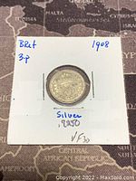 Front side of the 1908 silver 3 pence coin in holder with handwritten label showing year, origin, and silver content.