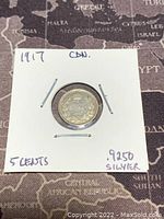 Front of the 1917 Canadian 5 cents silver coin in a cardboard holder showing year, denomination and silver content.