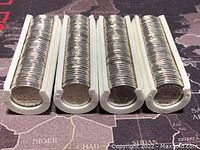 Four white plastic coin tubes filled with Canadian 5-cent coins laid side by side