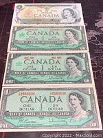 Four Canadian one dollar bills laid out with visible front sides showing Queen Elizabeth II.