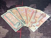 Six Canadian two-dollar banknotes arranged fanned out showing front sides, including 1954, 1974, and 1986 series.
