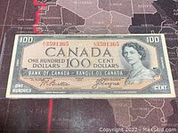 Front of $100 note showing full design: Queen Elizabeth II portrait at right, denomination panels, red serial number