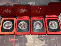 Four Canadian silver dollar coins in individual red velvet-lined presentation cases, showing both coin designs and case interiors.