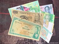 Seven assorted world banknotes spread out showing visible front designs including El Banco de Mexico, Zimbabwe and South African notes with numeric denominations and portraits.