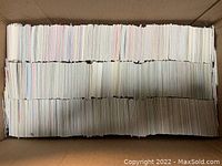 Top-down view of a large cardboard box filled with neatly arranged white-backed hockey trading cards showing mostly card backs