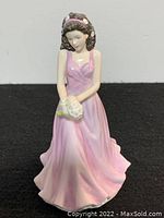 Front view of the figurine showing the young woman in a flowing pink dress holding a bouquet of daisies.
