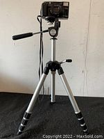 Black Minolta AF-Tele Super 35mm camera mounted on tripod, showing full height and tripod detail.