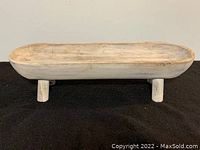 Wooden bowl with feet shown front view, highlighting the two supporting legs and overall shape.