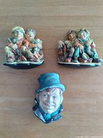 Overview of the two Naturecraft figurines and Bossons ceramic face displayed on wooden surface.