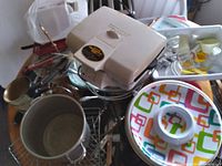 Overview of kitchen items showing white four-slice toaster, colorful serving bowl, metal pots, utensils and wire racks.
