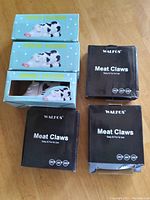 Photo of three Animal Vacuum toy boxes and three Meat Claw boxes stacked on a wooden surface.