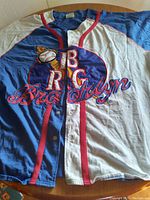 Front view of RBC Brooklyn baseball jersey showing overall design and color scheme with detailed embroidered logo and baseball patch on chest along red-button lined closure.