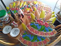 Photo of table displaying colorful Thanksgiving plaques, Happy Thanksgiving signs, Santa figurine, Christmas tree-shaped candles, ceramic plates, and small figurines arranged for sale.