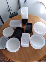Overview of assorted food storage containers of different shapes and sizes arranged on a wooden table.