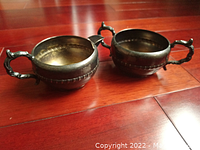 Two vintage Viking Plate branded E.P. copper pieces, a sugar bowl and creamer, both with patina and detailed handles, shown from top and side angle on wooden flooring.