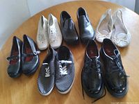 Photograph showing seven pairs of women's shoes of various styles and sizes arranged on a circular wooden table.