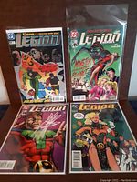 Four Legion of Super-Heroes comic books from DC Comics shown in protective plastic sleeves on a surface. Covers show 1990s stylized superheroes.