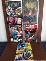 Five Batman comics standing and lying on a flat surface showing front covers.