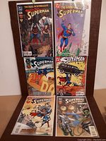 Photo showing six Superman comic books from DC Comics arranged closely, with colorful covers mostly depicting Superman in various action scenes and storylines from the 1990s.