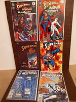 Photo showing six Superman comic books, two of 'The Superman and Madman' series, 'Superman Gal', and three others including 'Superman Doomsday' and 'The Death of Superman Man of Steel'. Covers show colorful comic art from the 1990s.