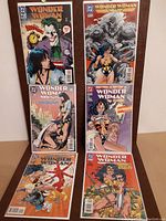 Six Wonder Woman comic books arranged for display, showing colorful covers from the 1990s era including Joker and other characters.