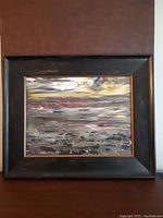 Full view of framed painting showing textured black wood frame and abstract seascape