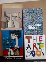 Four art books in a flat lay featuring Sotheby's catalogue, Encyclopedie van de Moderne Kunst, The Art Book, and Pablo Picasso book with colorful cover art.