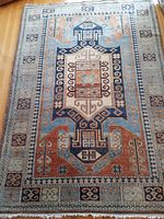 Full view of the rug showing overall design, including central medallion and border pattern, on a hardwood floor.