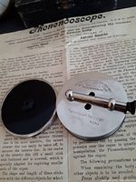 Phonendoscope device with metal crank, circular diaphragm with markings, and original instruction sheet visible beneath showing detailed text.