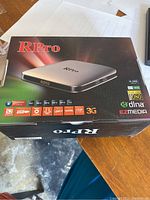Photo of the RPro Android TV Box in retail packaging, showing front and side with product features.