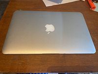 Closed laptop top view on wooden surface showing Apple logo and casing condition