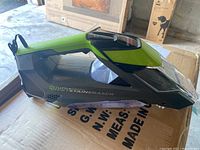 Side angled view of Bissell Little Green Pet Hair Eraser portable carpet cleaner showing green and black coloring, transparent front cleaning reservoir and handle.