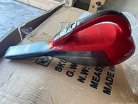 Side angle of Black+Decker chili red handheld vacuum on cardboard box showing the full device and branding on nozzle.