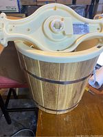 Photo of vintage-style ice cream maker showing wooden bucket, metal bands, and top hand crank mechanism.