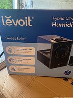 Photo of the Levoit hybrid ultrasonic humidifier box showing the product image and features including Sweet Relief branding and that it offers soothe symptoms, highly effective range, aromatherapy.