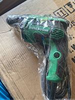 Photo showing green and black Metabo HPT right angle drill wrapped in plastic, new condition.