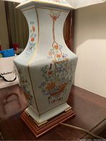 Close-up of the ceramic lamp base showing detailed floral hand-painted patterns and gold accents.