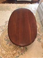 Top view of an oval mahogany coffee table showing blood wood grain and scratches on the surface.