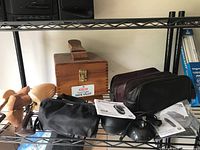 Photo showing electric razor, carrying case, shoe shine kit box, polishing cloths, and cords on a metal rack.