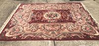Full front-facing view of the large burgundy rug laid out flat showing floral patterns and beige borders.