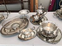 Photo showing entire collection of silver plated serving dishes and tea set on table.