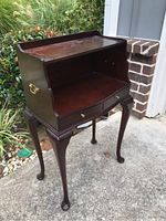 Front view of the small mahogany desk showing the open workspace, two front drawers with brass knobs, and cabriole legs.