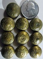 Top view of 10 brass Boston & Maine Railroad buttons alongside a US quarter for size reference.