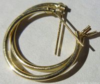 Close-up photo of the pair of small rounded 14K gold hoop earrings with hinged clasp.