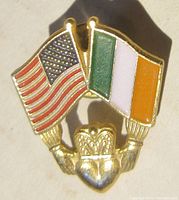 Front view of the gold tone pin showing the American and Irish flags above the Claddagh symbol.