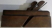 Side view of the antique wood block plane showing the wooden body and double blades.