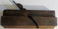 Side view of the wooden molding plane showing the angled blade and surface wear.