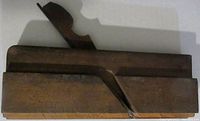 Top view of antique wooden molding plane showing block body and angled iron blade