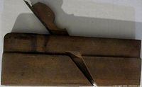 Side angled view of the antique wooden molding plane showing the blade and body profile.